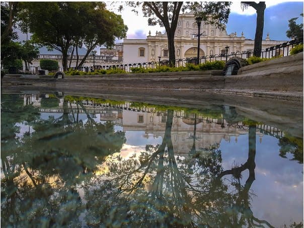 The cathedral of Antigua Guatemala reflected in a puddle on the Plaza Mayor after the rain