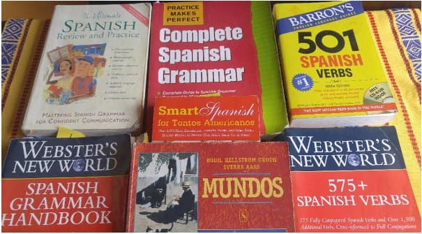 A pile of Spanish grammar books: 501 Spanish Verbs, Complete Spanish Grammar, Webster’s New World Spanish Grammar Handbook and others