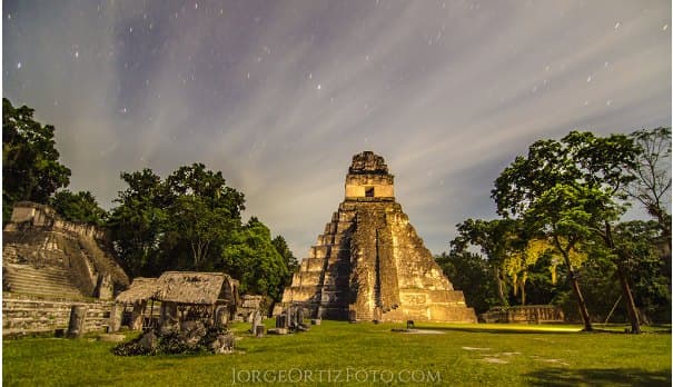 The main temple of Tikal at night under a starry sky, surrounded by jungle