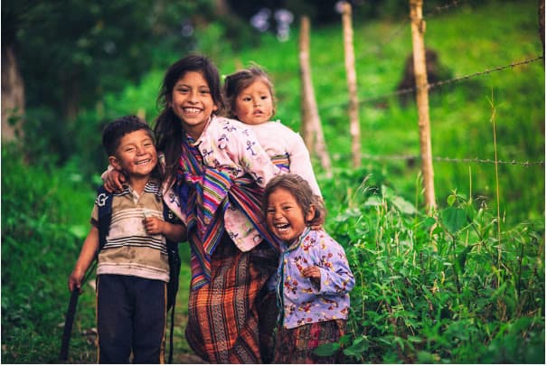 Four children laughing in a green field in southern Guatemala